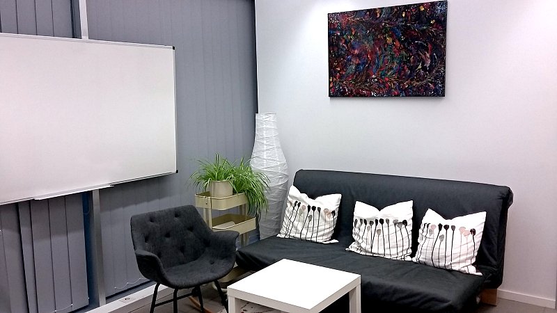 Besprechungszimmer mit Couch, Tisch und Tafel